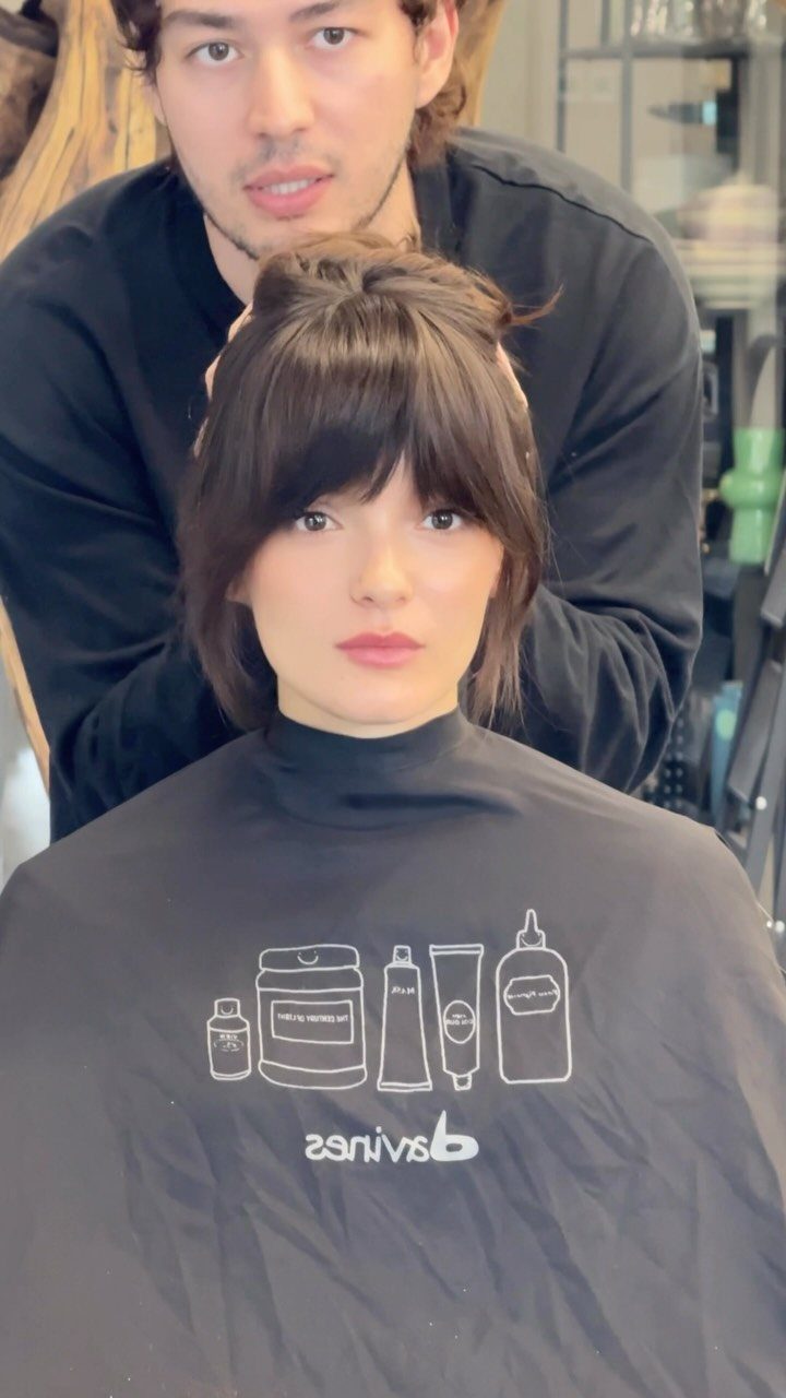 Woman with dark brown shaggy bangs and a stylist in a hair salon.