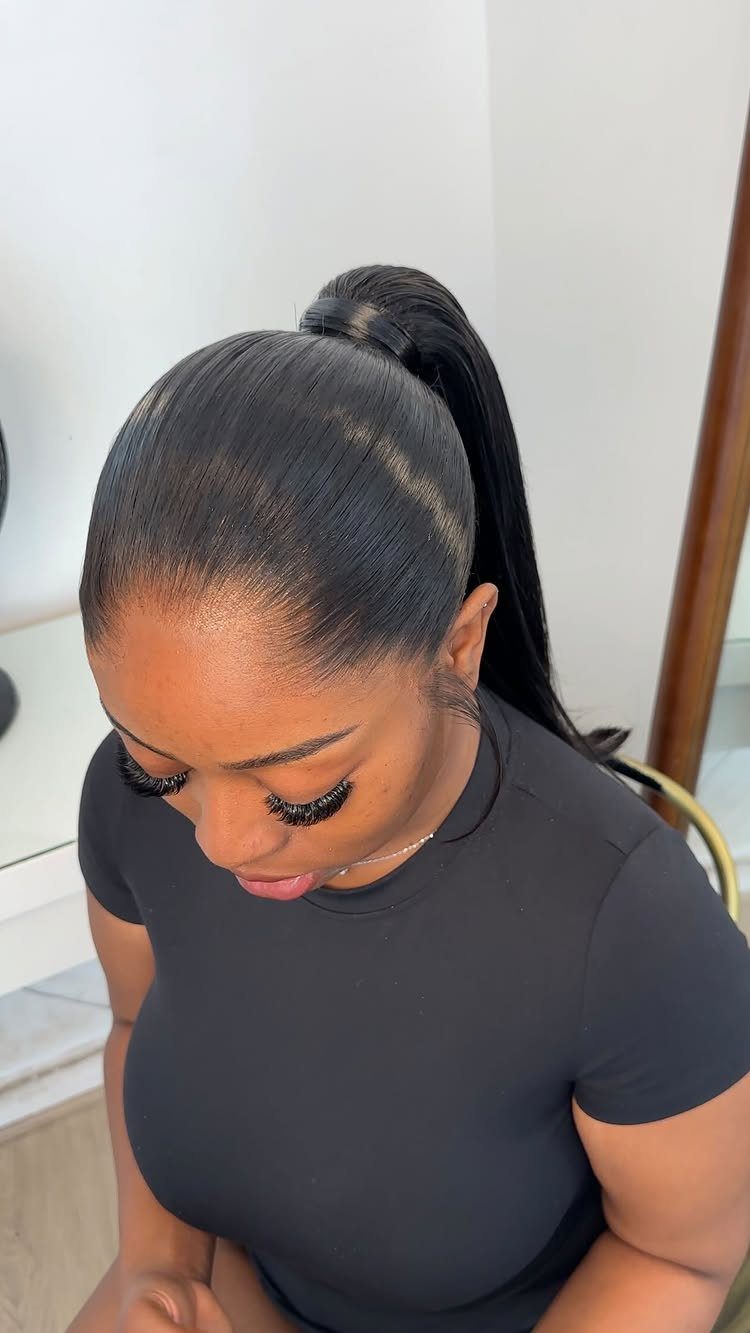 Woman with a high, sleek, voluminous black ponytail wearing a black t-shirt.