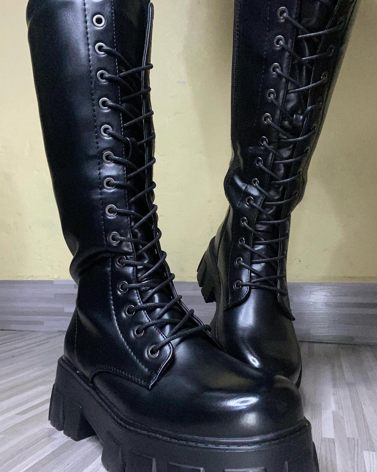Cute Long Boots: 10 Ideas, From Combat to Over the Knee 3 Black leather lace-up combat boots with chunky soles on a wooden floor.