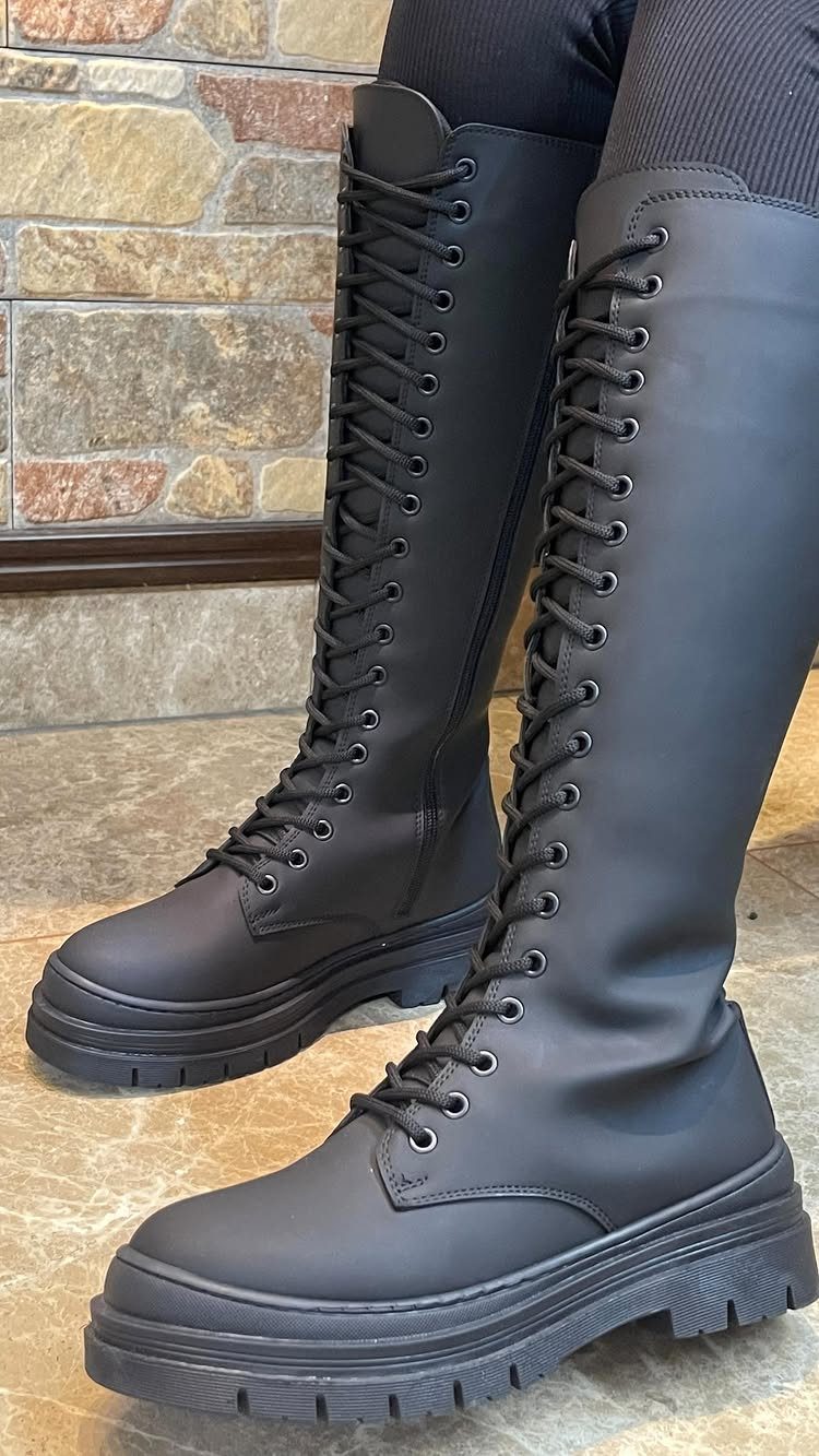 Cute Long Boots: 10 Ideas, From Combat to Over the Knee 7 Knee-high black lace-up boots with chunky soles worn with black leggings.