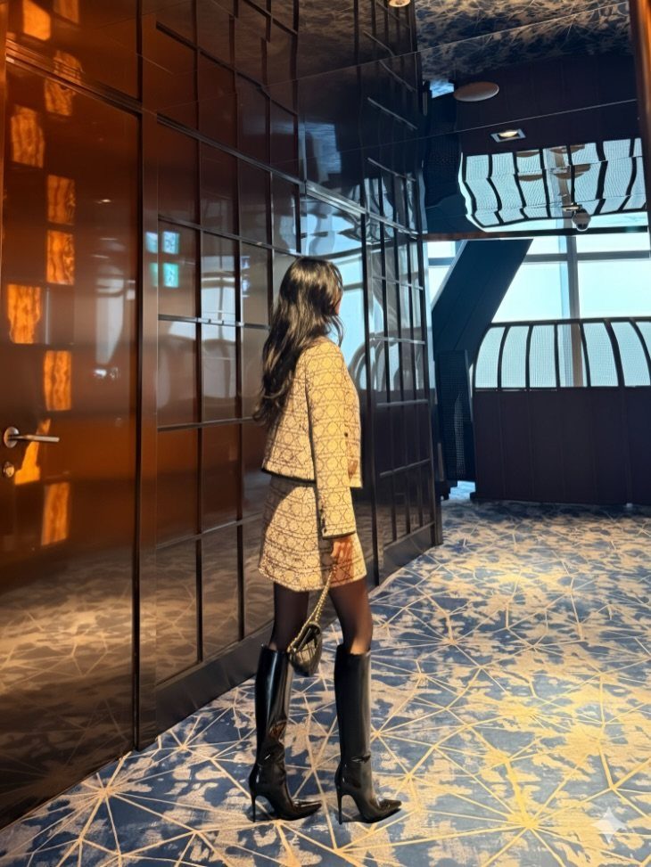 Cute Long Boots: 10 Ideas, From Combat to Over the Knee 10 Woman in a tweed suit wearing black high-heeled long boots in a hallway