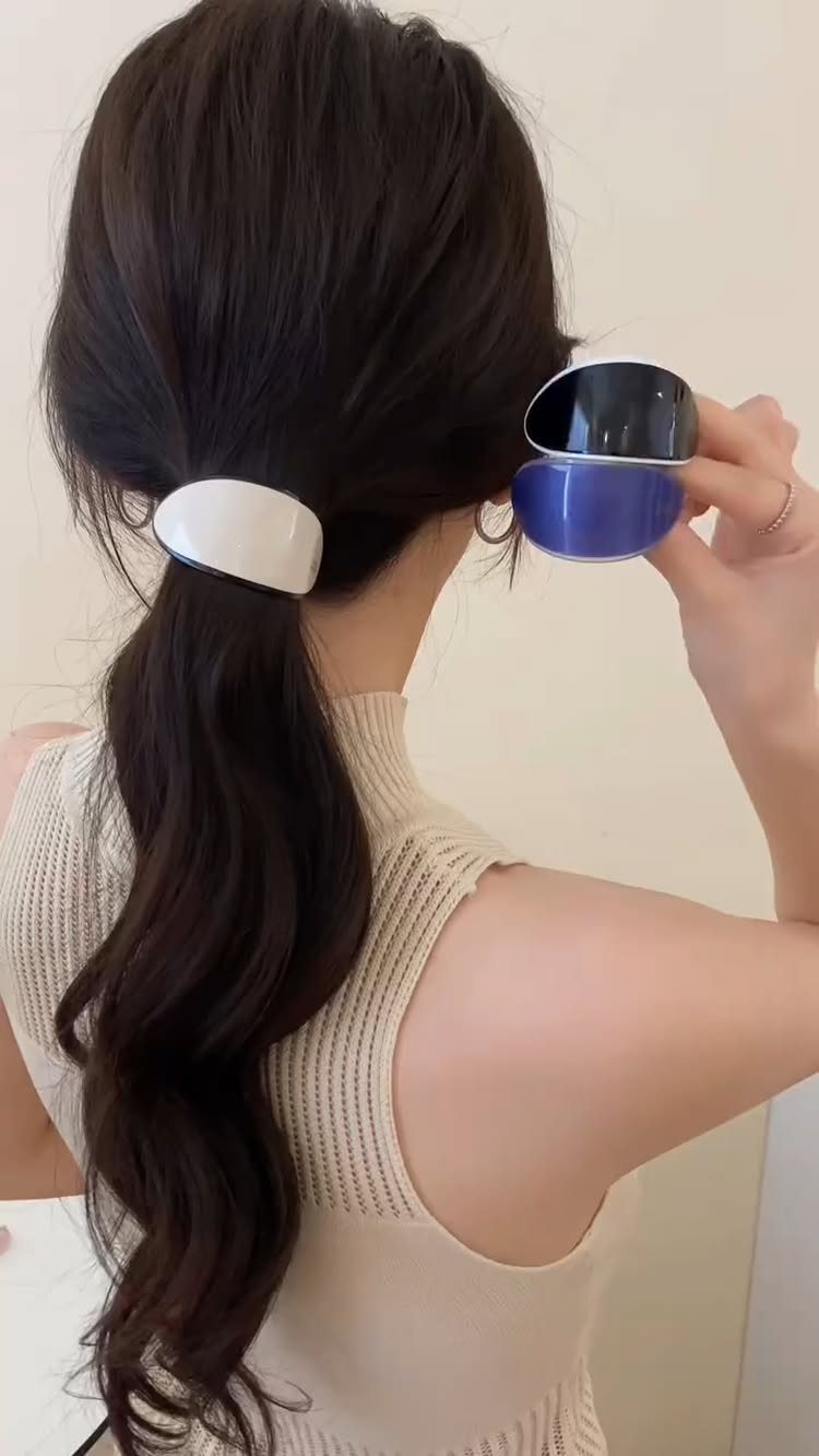 18 Cute Ponytail Hairstyles for Every Mood and Length 14 Woman with long brown wavy hair in a low ponytail with white barrette