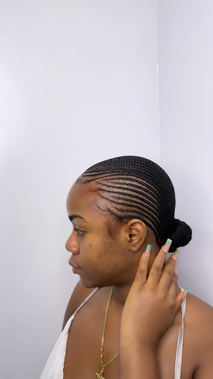 18 Cute Ponytail Hairstyles for Every Mood and Length 7 Woman with cornrow braids gathered into a low ponytail bun against white background