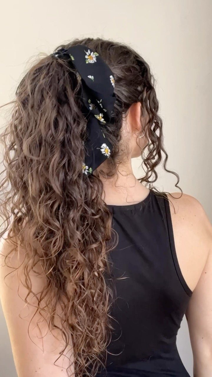 18 Cute Ponytail Hairstyles for Every Mood and Length 6 Curly brown hair tied in a ponytail with a black floral scrunchie.