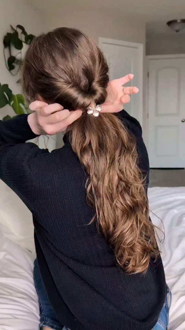 18 Cute Ponytail Hairstyles for Every Mood and Length 18 Woman with long wavy brown hair in a ponytail with a flower clip.