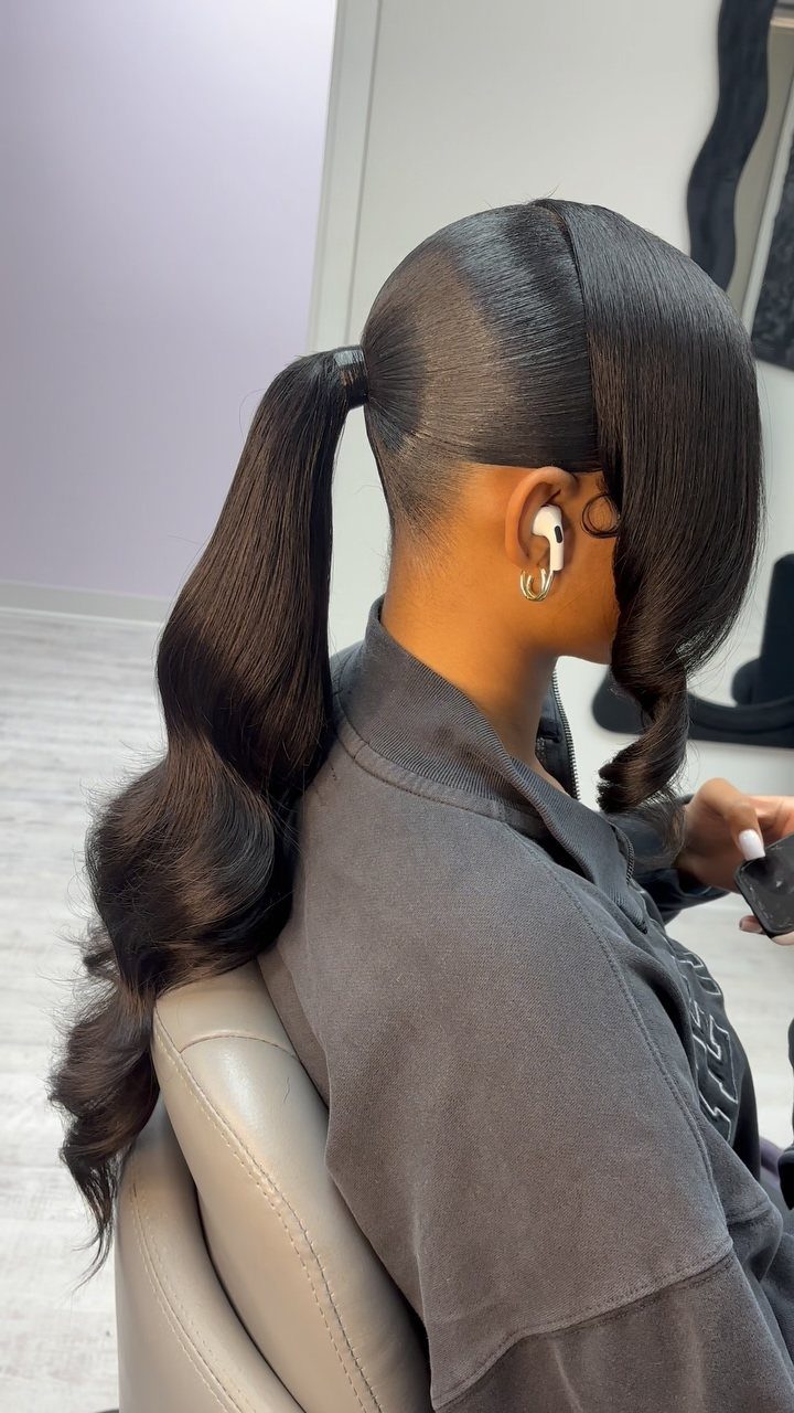 18 Cute Ponytail Hairstyles for Every Mood and Length 3 Woman with a sleek high ponytail and wavy ends wearing a grey shirt.