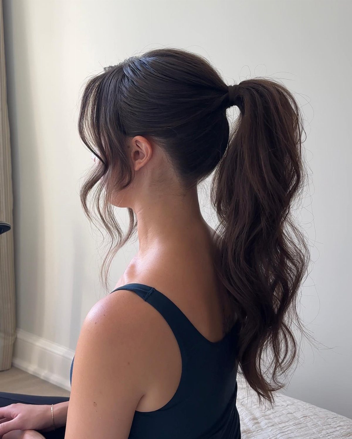 18 Cute Ponytail Hairstyles for Every Mood and Length 13 Woman with a high wavy ponytail and a loose strand framing her face.