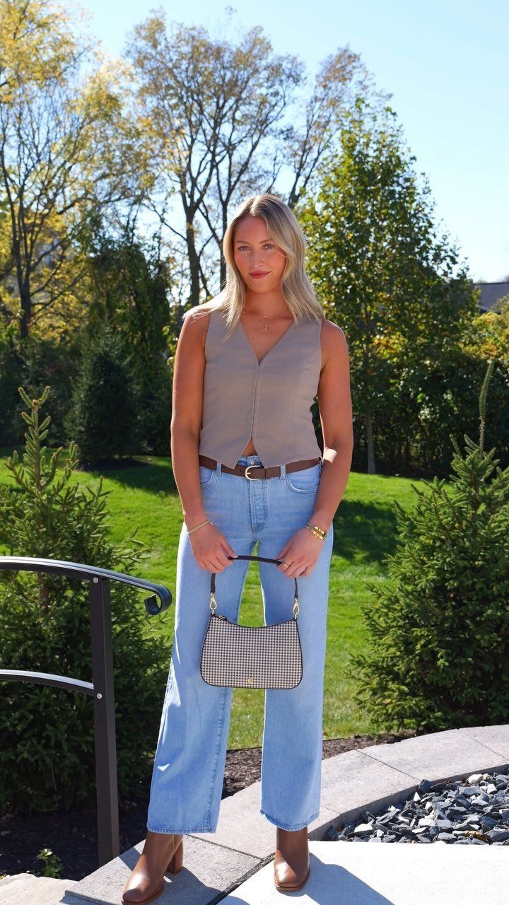 Cute Western Outfits for Women: 13 Ideas to Wear Now 6 Woman wearing light blue boot-cut western jeans, tan vest, and brown heeled boots.