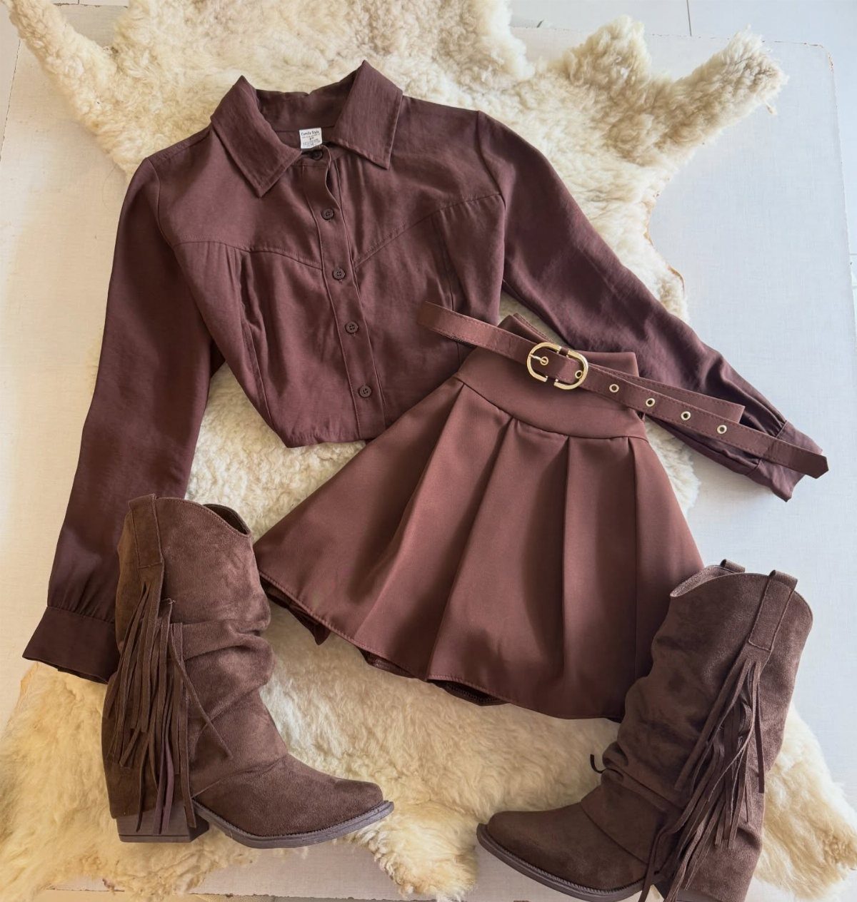 Cute Western Outfits for Women: 13 Ideas to Wear Now 13 Brown button-up shirt, pleated mini skirt, and fringe boots on a white rug.