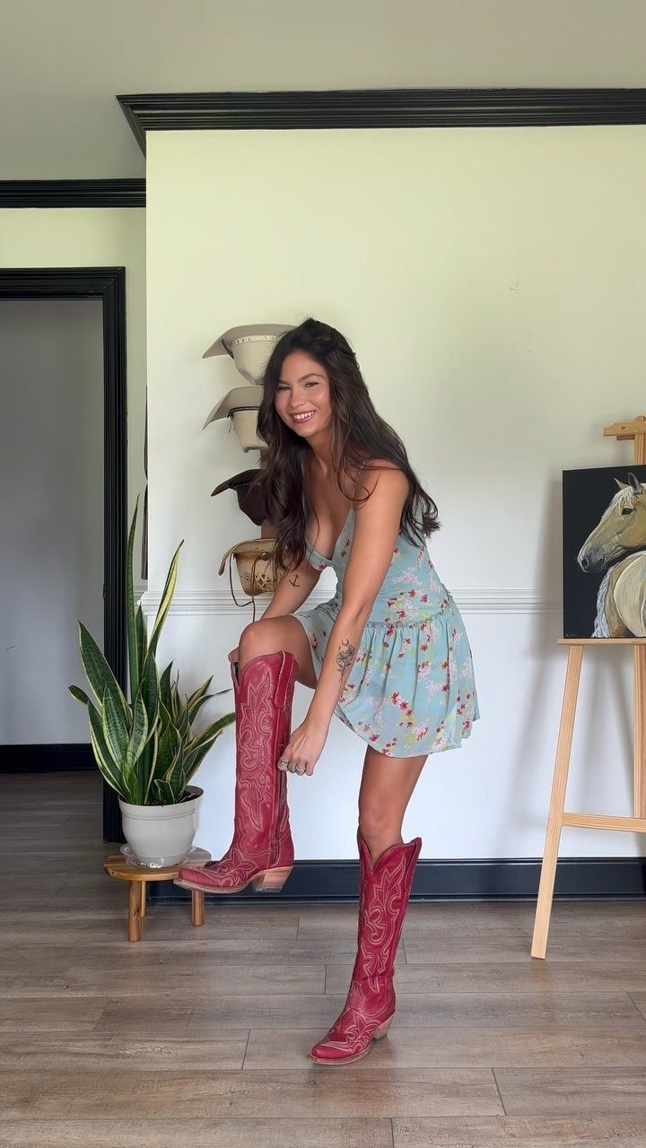Cute Western Outfits for Women: 13 Ideas to Wear Now 1 Woman in a floral mini dress wearing tall red leather cowgirl boots.