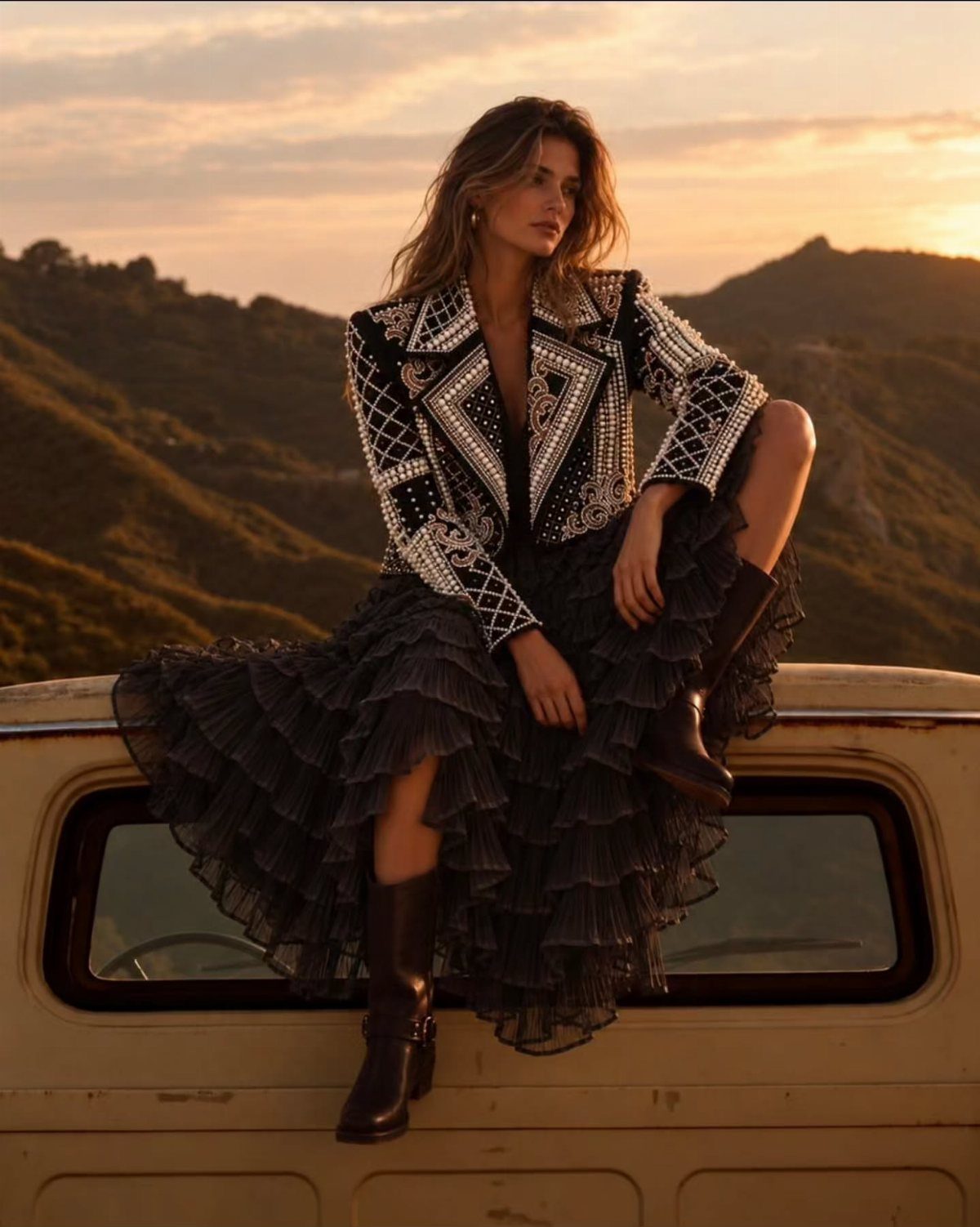 Cute Western Outfits for Women: 13 Ideas to Wear Now 4 Woman in embroidered jacket, ruffled black skirt, and cowgirl boots on a truck.
