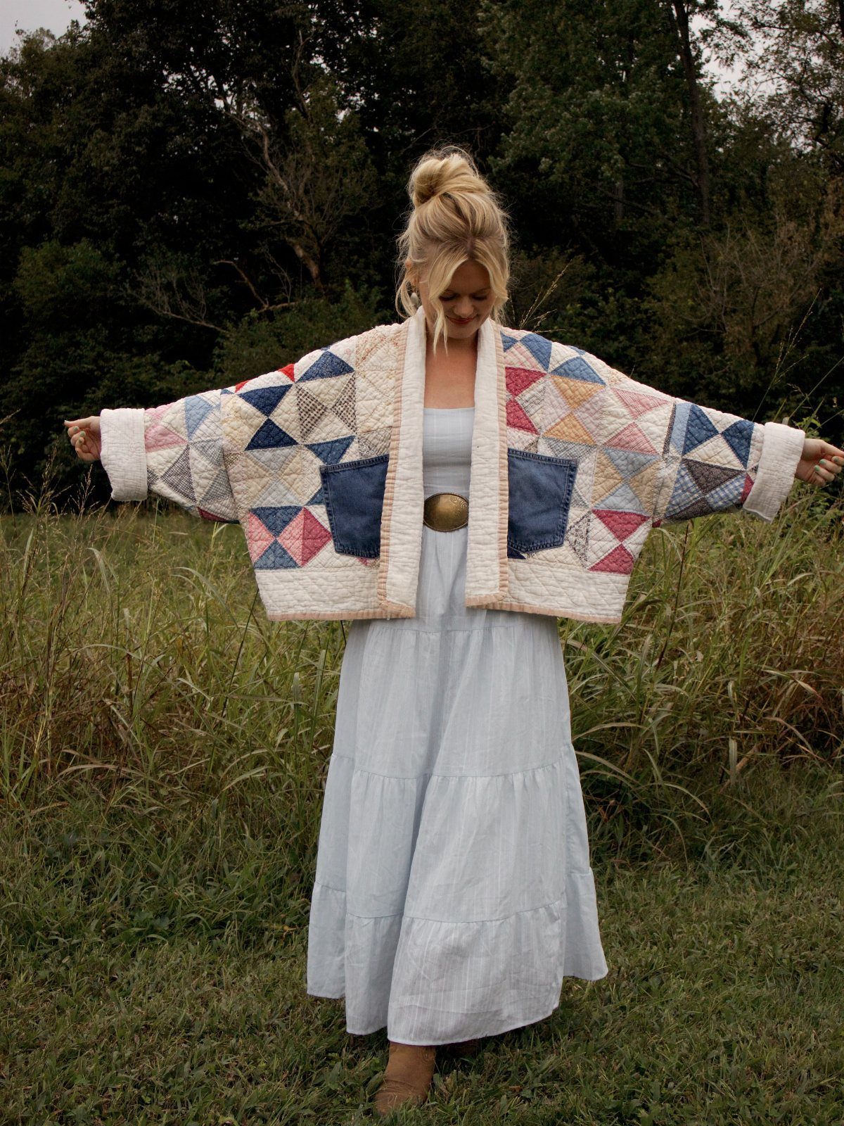Cute Western Outfits for Women: 13 Ideas to Wear Now 11 Woman in a light blue tiered dress and colorful patchwork quilted jacket in field