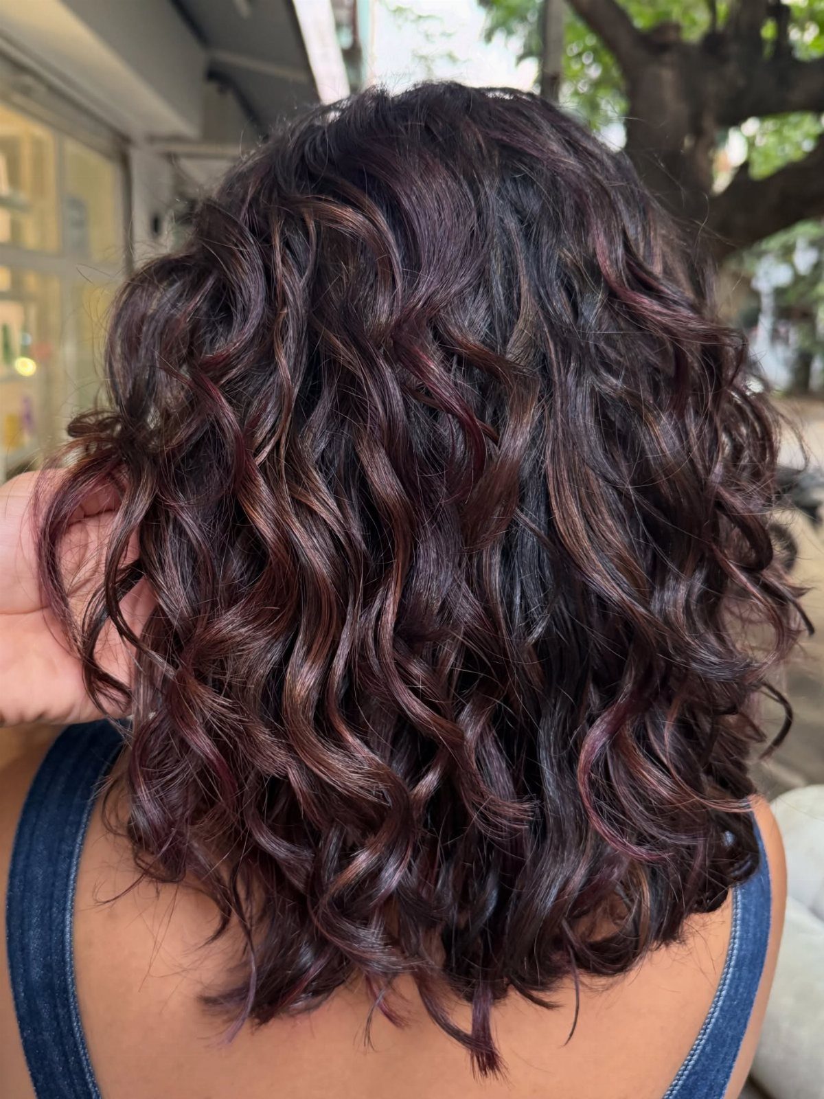 5 Dark Crimson Hair Ideas, From Merlot to Copper Tones 3 Curly shoulder-length hair with a blend of deep auburn and red balayage tones.