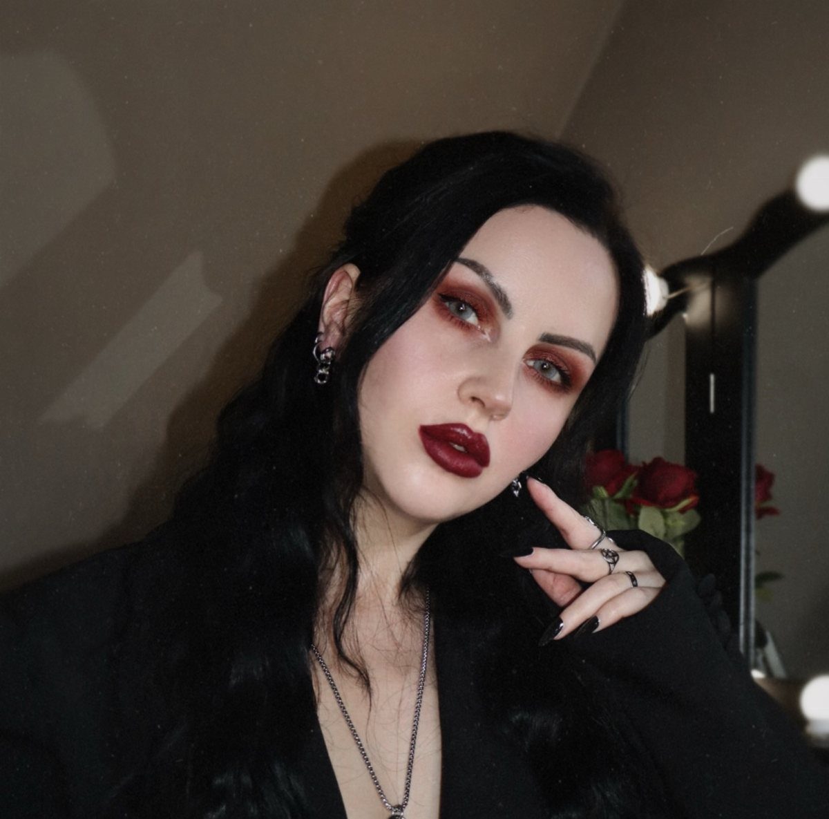 Woman with dark feminine aesthetic featuring red makeup, black blazer, and long hair.