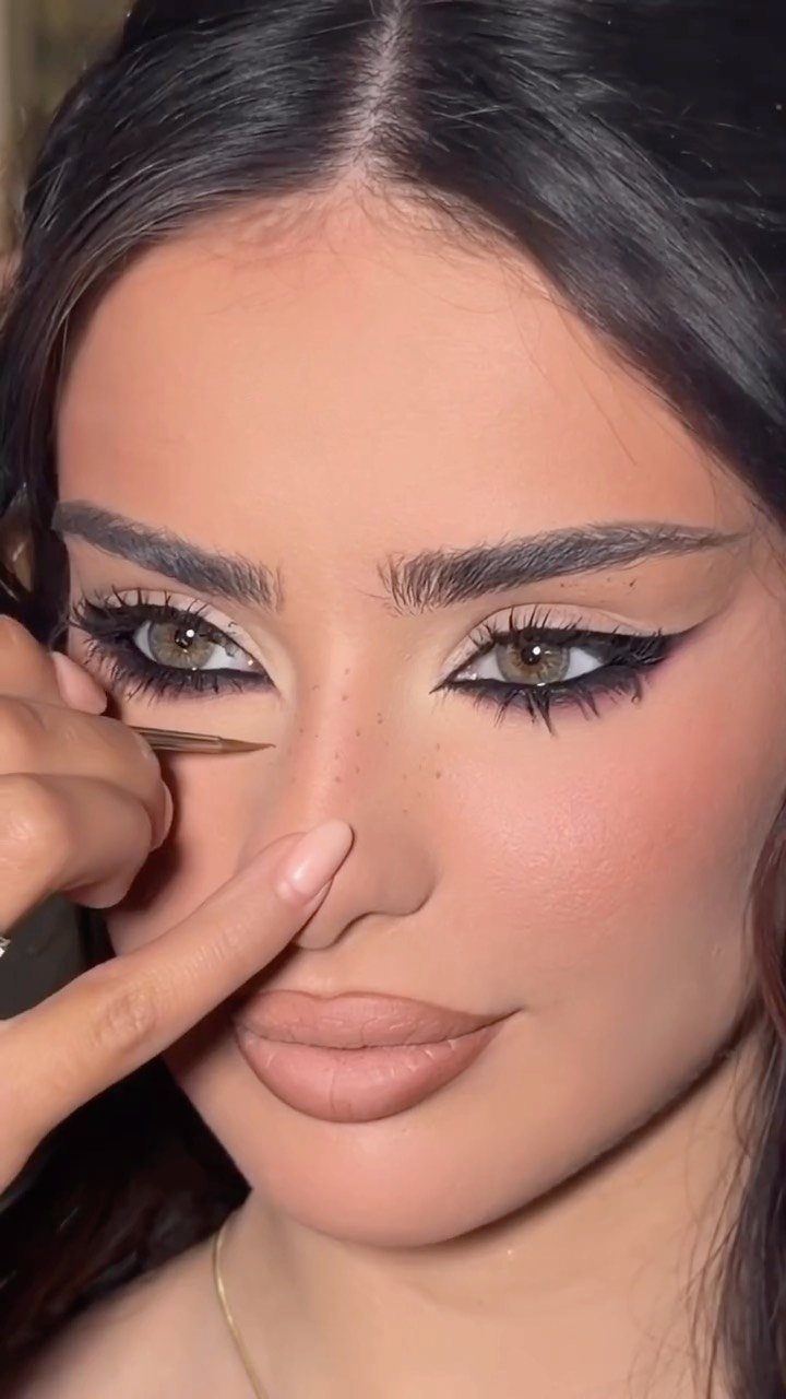 Woman with dramatic winged eyeliner and contoured makeup receiving a makeup touch-up.