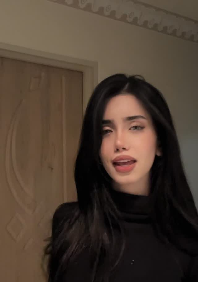 Woman with long sleek dark hair wearing a black turtleneck top.