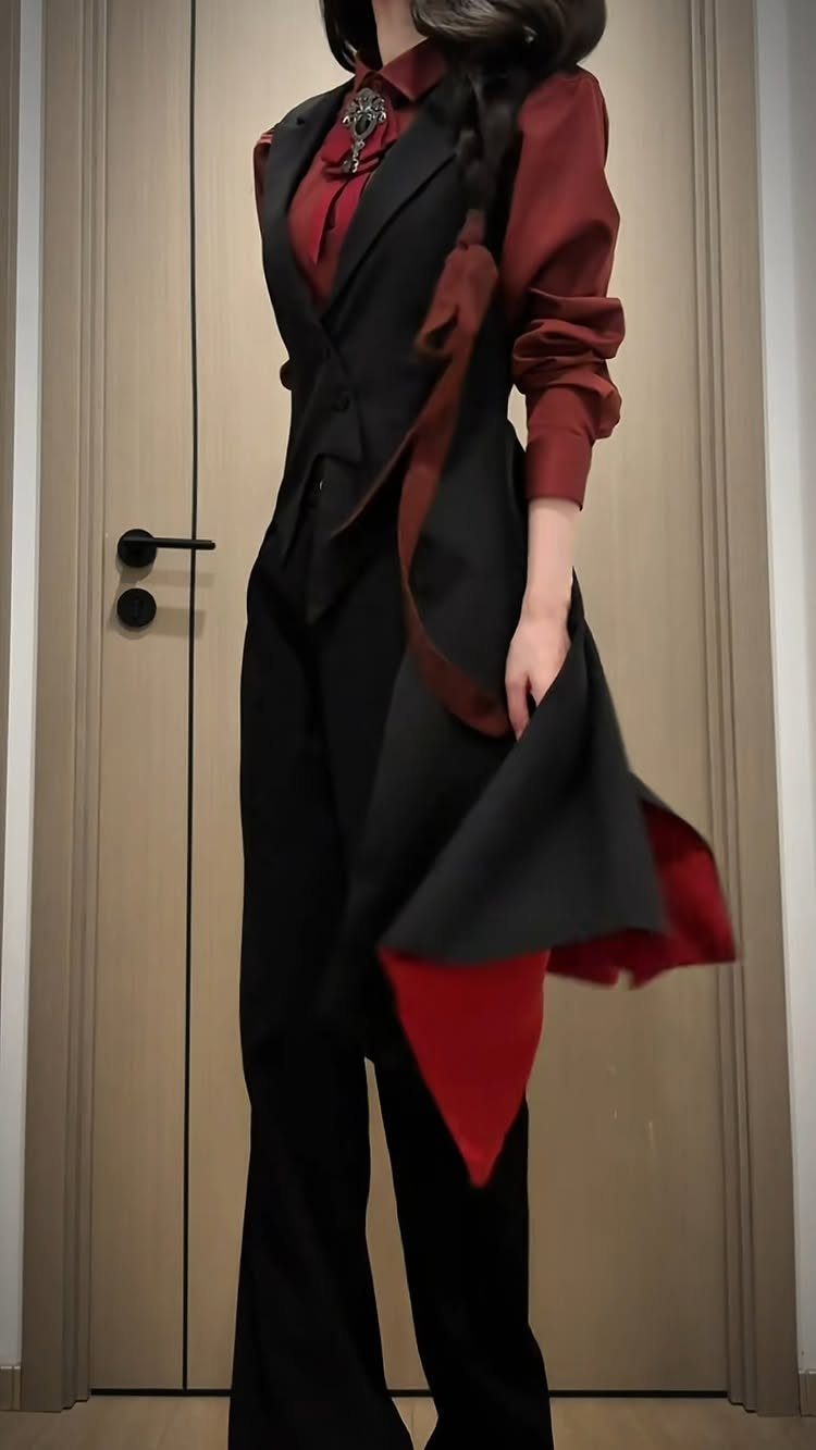Person in a red shirt and black tailored vest with wide-leg trousers.