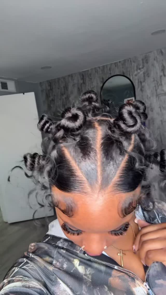 Person with defined 4c hair styled in glossy curls and small buns.