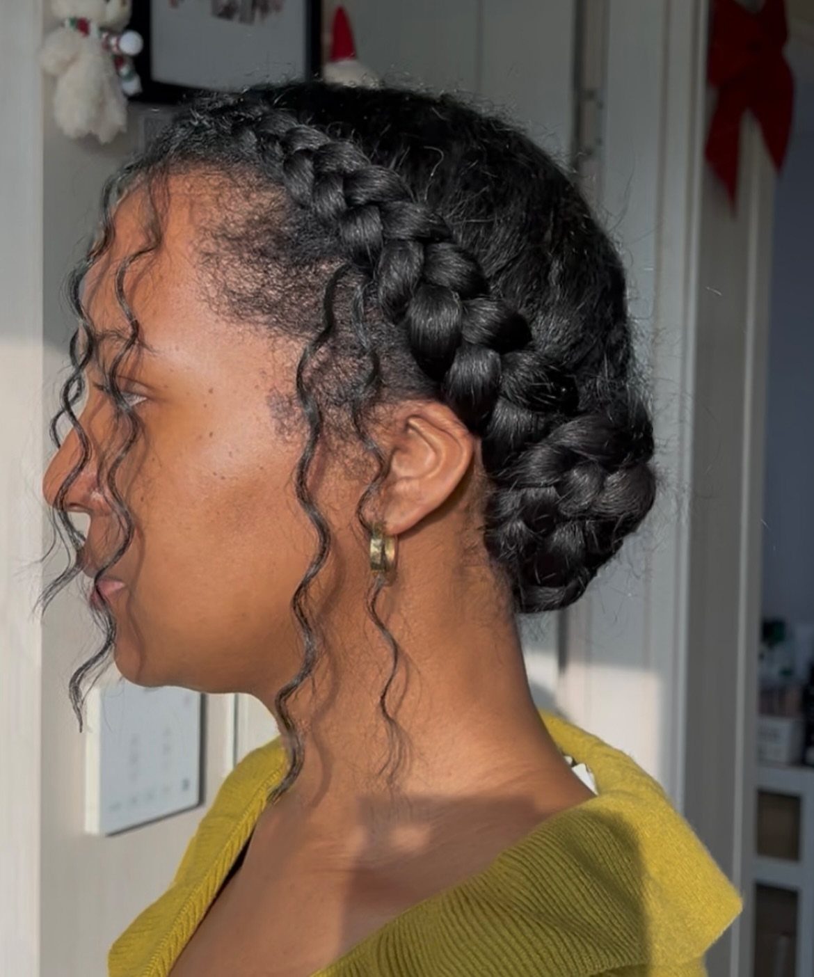 Woman with dark 4c hair styled in a side braid and curly tendrils.