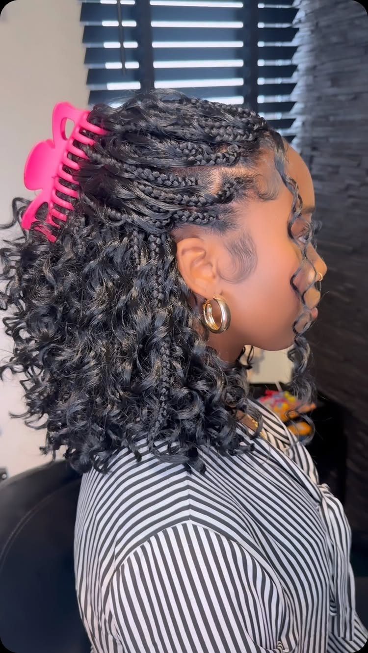 Woman with black boho braids featuring curly ends and a pink claw clip.