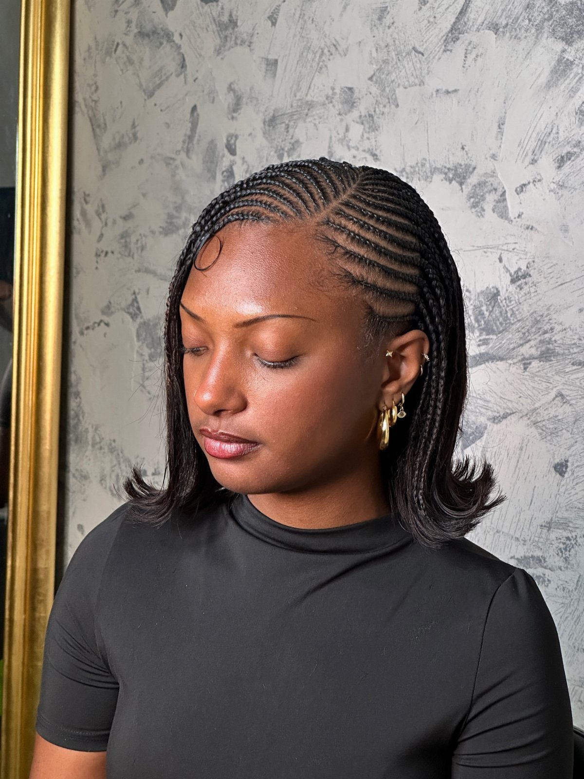 Woman with a braided bob hairstyle featuring cornrows and curled ends.