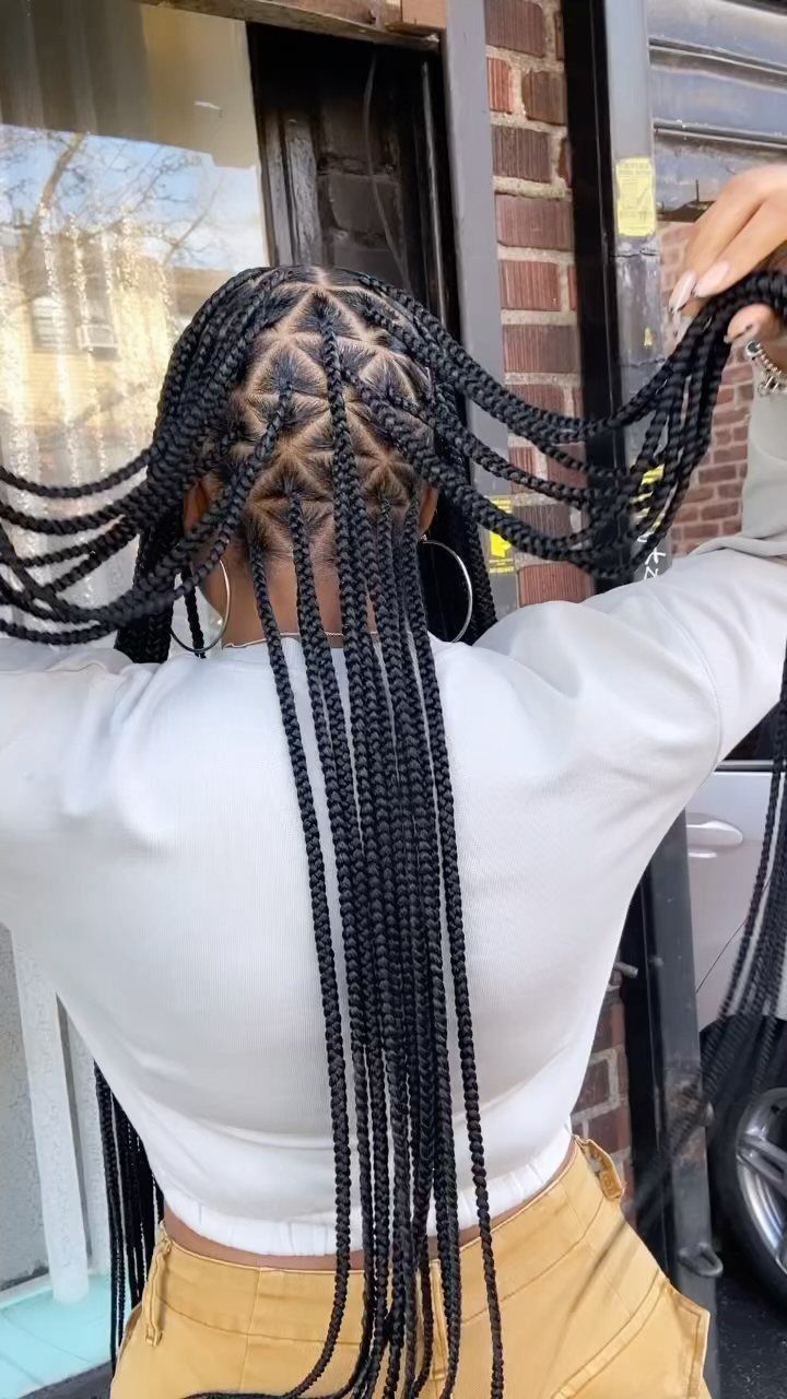 Long black cornrows braided flat against the scalp transitioning into hanging braids.