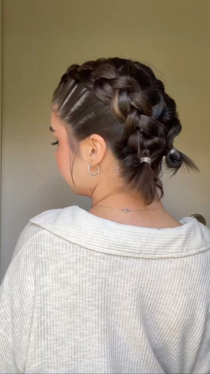 Woman with dark brown hair styled in thick, raised Dutch braids across the back.