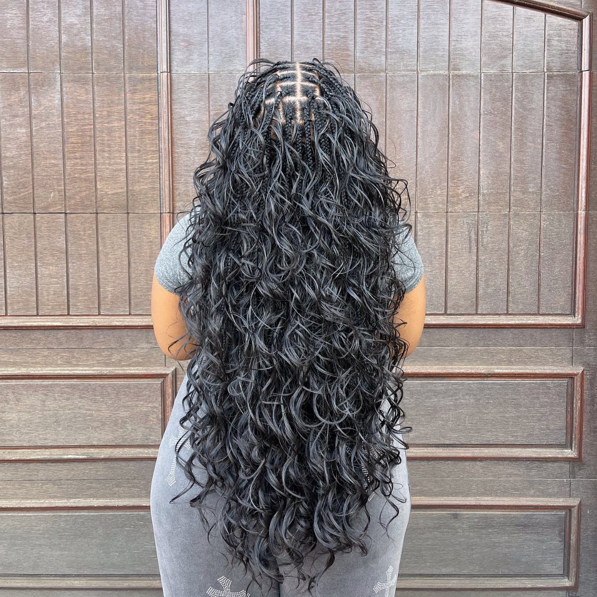 Long black French curl braids with a geometric scalp pattern and curly ends.
