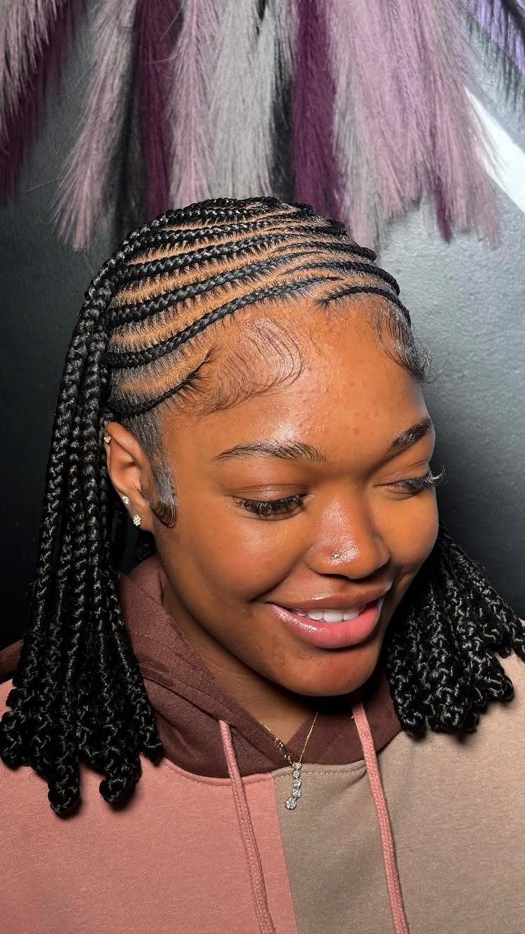 Woman with black Fulani braids featuring cornrows and individual plaits, smiling in a hoodie.
