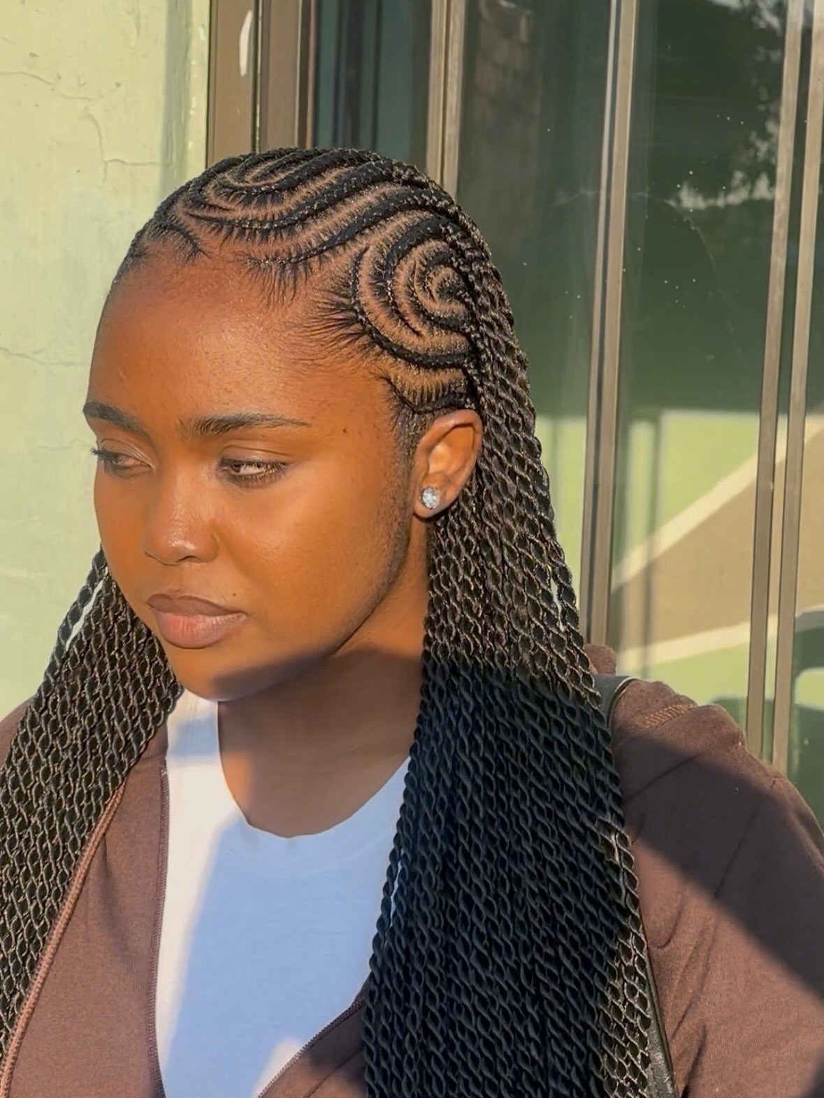 Woman with curved cornrow braids transitioning into long, dark hanging braids.