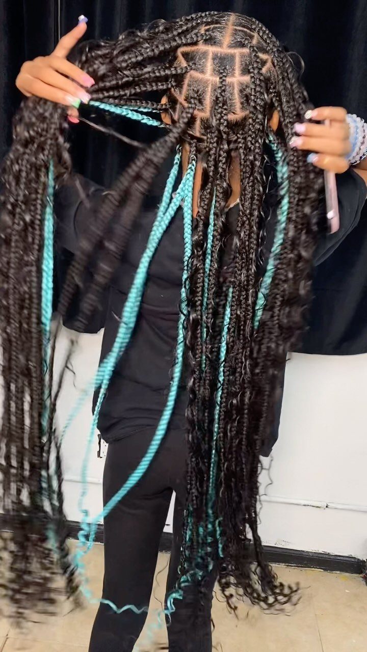 Long dark box braids with bright turquoise blue highlights woven throughout the hair.