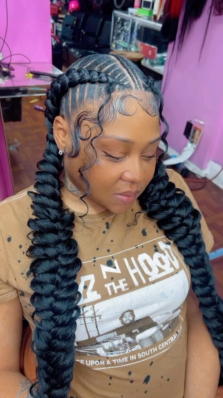 Woman with long, thick black twisted braids styled into two voluminous pigtails.