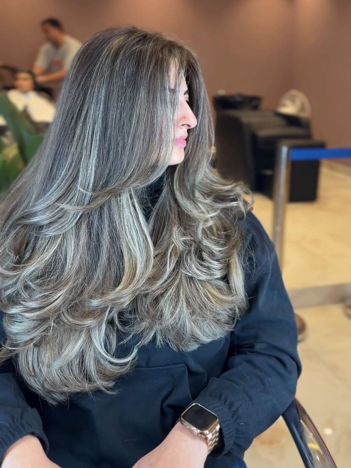 14 Different Color Hair Ideas for Every Skin Tone 5 Woman with long layered ash brown hair and cool blonde highlights in salon