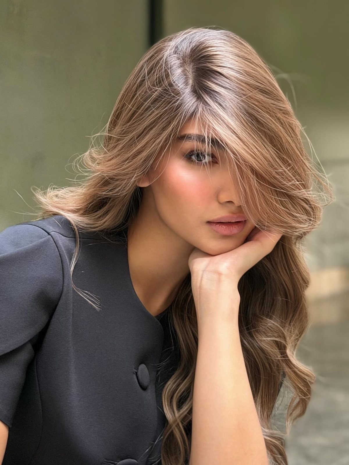 14 Different Color Hair Ideas for Every Skin Tone 3 Woman with long wavy brunette hair and golden highlights wearing a black blazer.