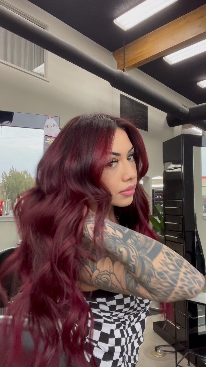14 Different Color Hair Ideas for Every Skin Tone 7 Woman with long wavy deep red hair and arm tattoos in a salon