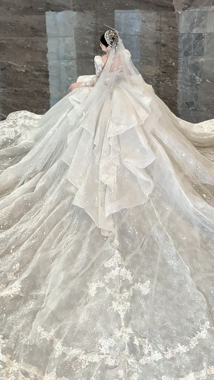 Voluminous white wedding gown with a long sparkling train and sheer veil.