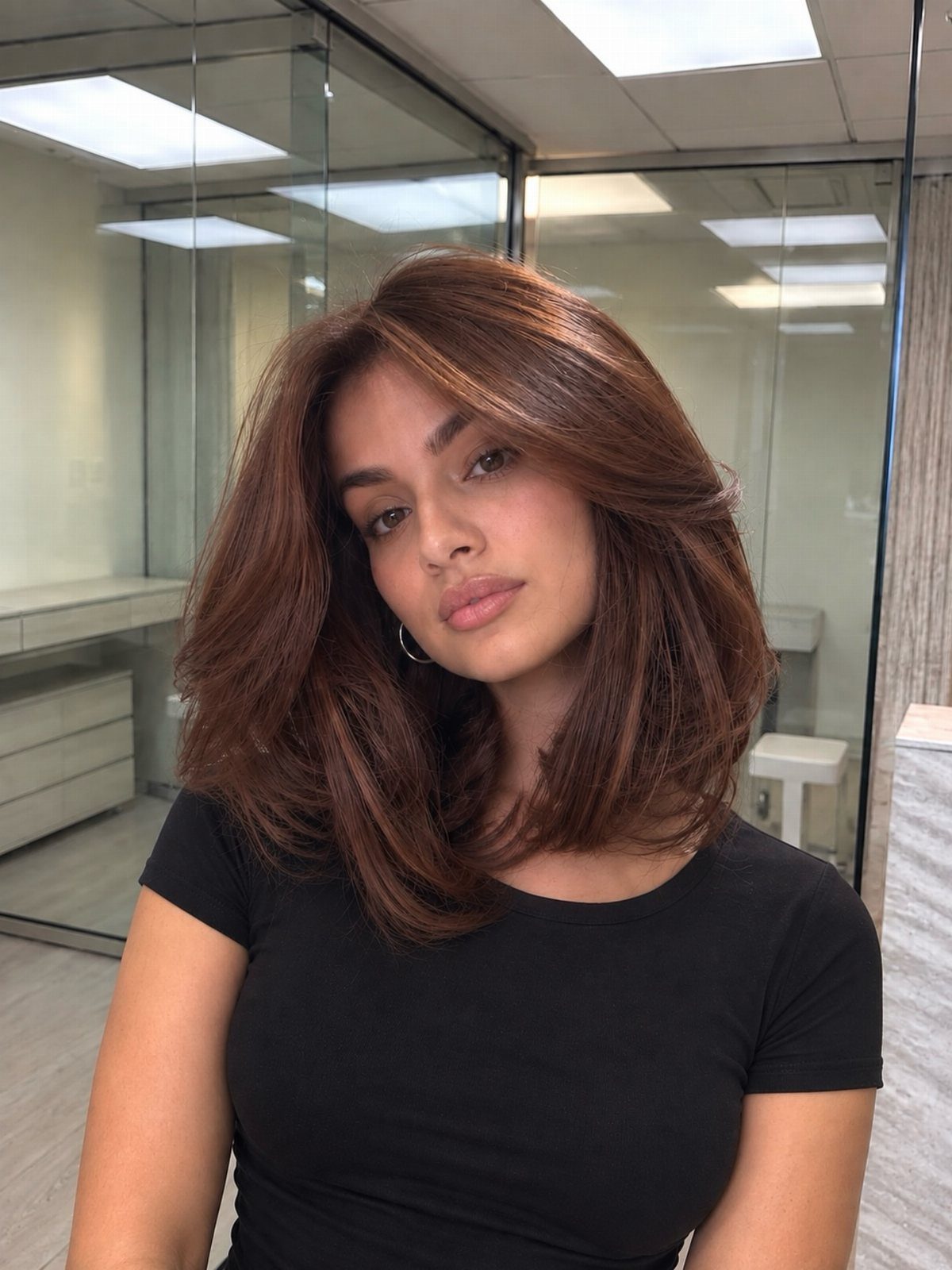 Fall Hairstyles and Color: 16 Ideas, Caramel to Espresso 3 Woman with voluminous chestnut brown hair and warm highlights wearing a black shirt.
