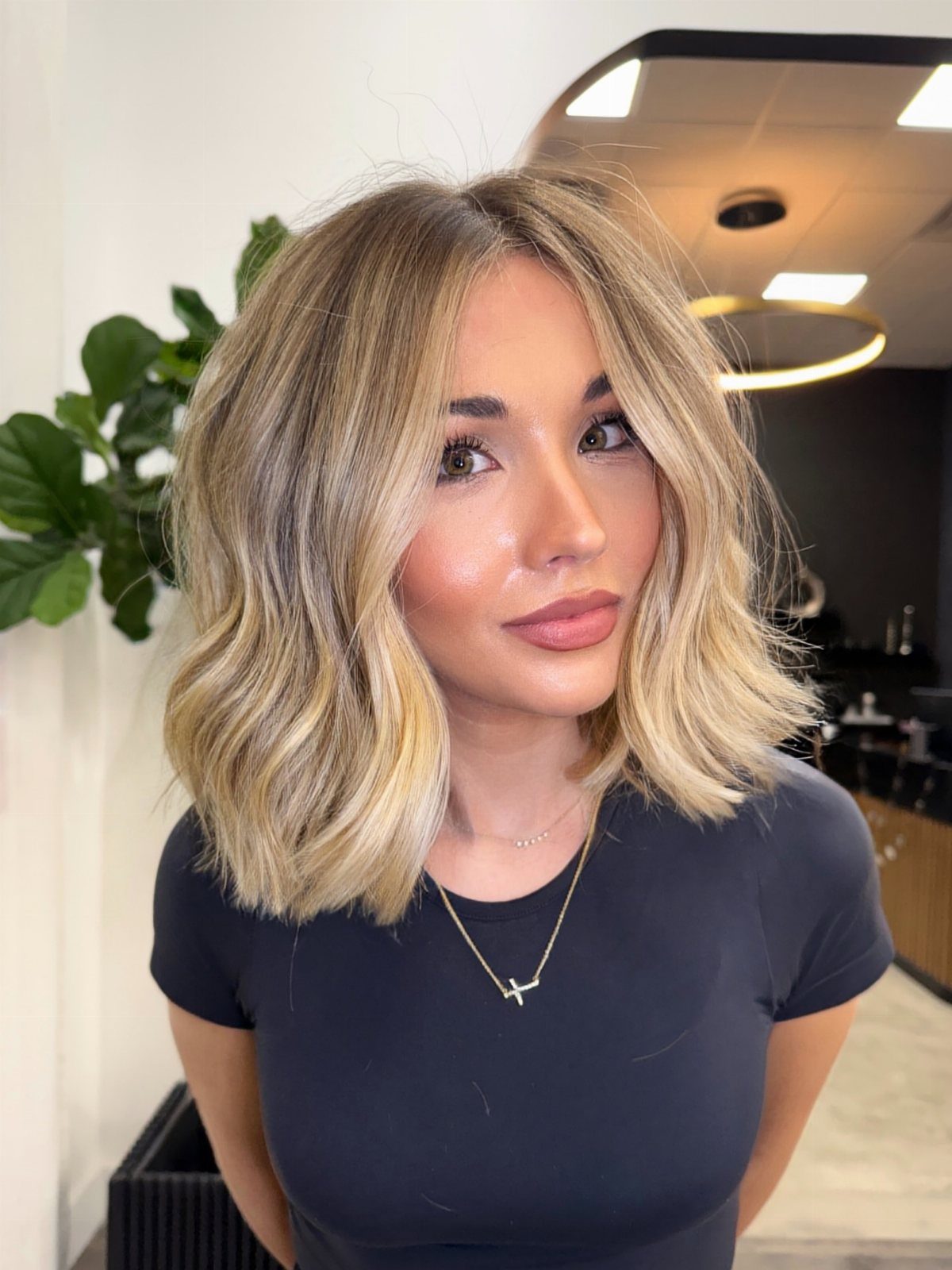 Fall Hairstyles and Color: 16 Ideas, Caramel to Espresso 5 Woman with wavy honey-blonde hair and light brown roots wearing a black shirt.