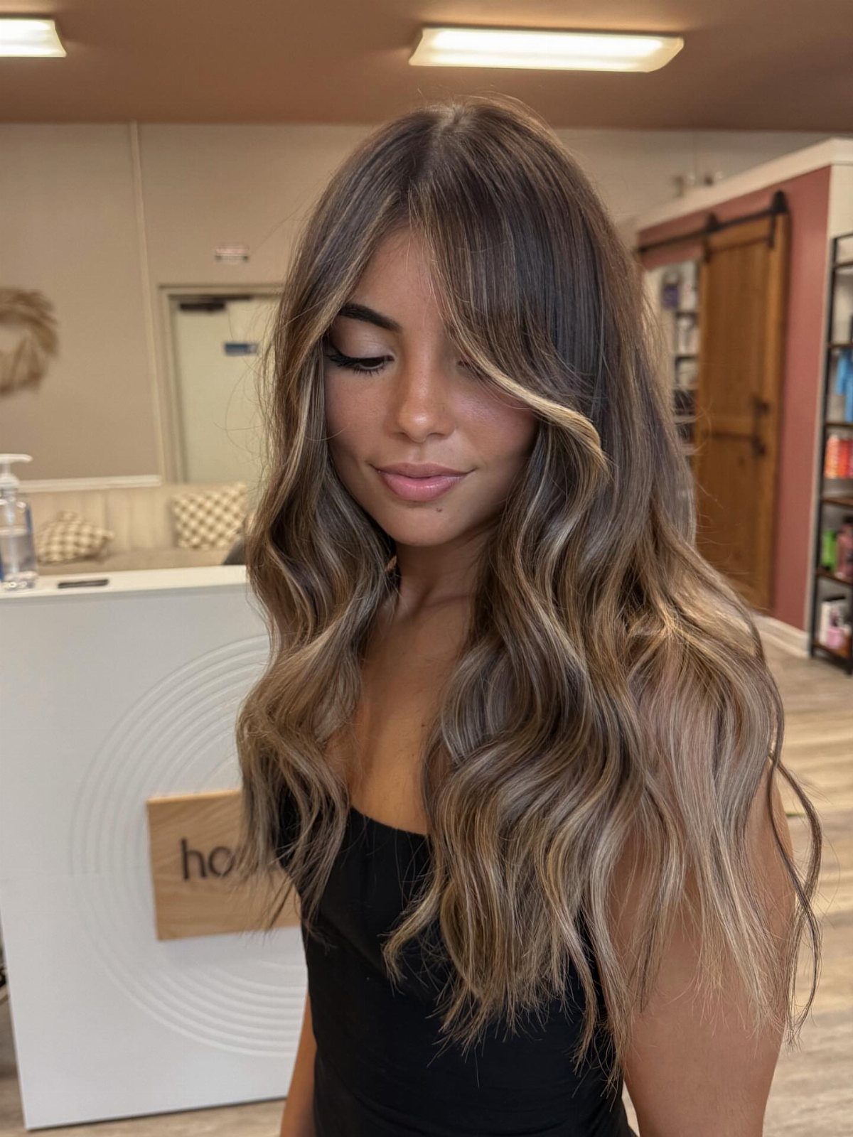 Fall Hairstyles and Color: 16 Ideas, Caramel to Espresso 12 Woman with wavy brown hair and golden blonde highlights in a hair salon