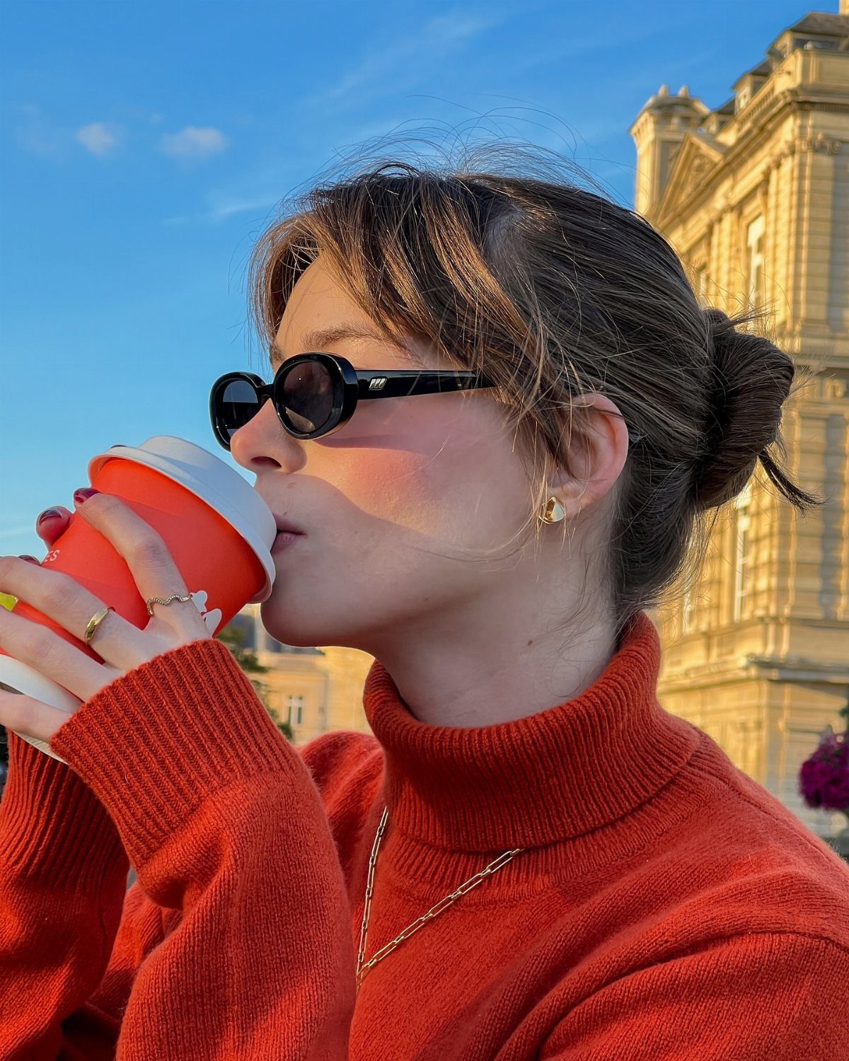 Fall Orange Outfits: 10 Ideas for Every Occasion 7 Woman in a burnt orange turtleneck sweater drinking from an orange coffee cup.