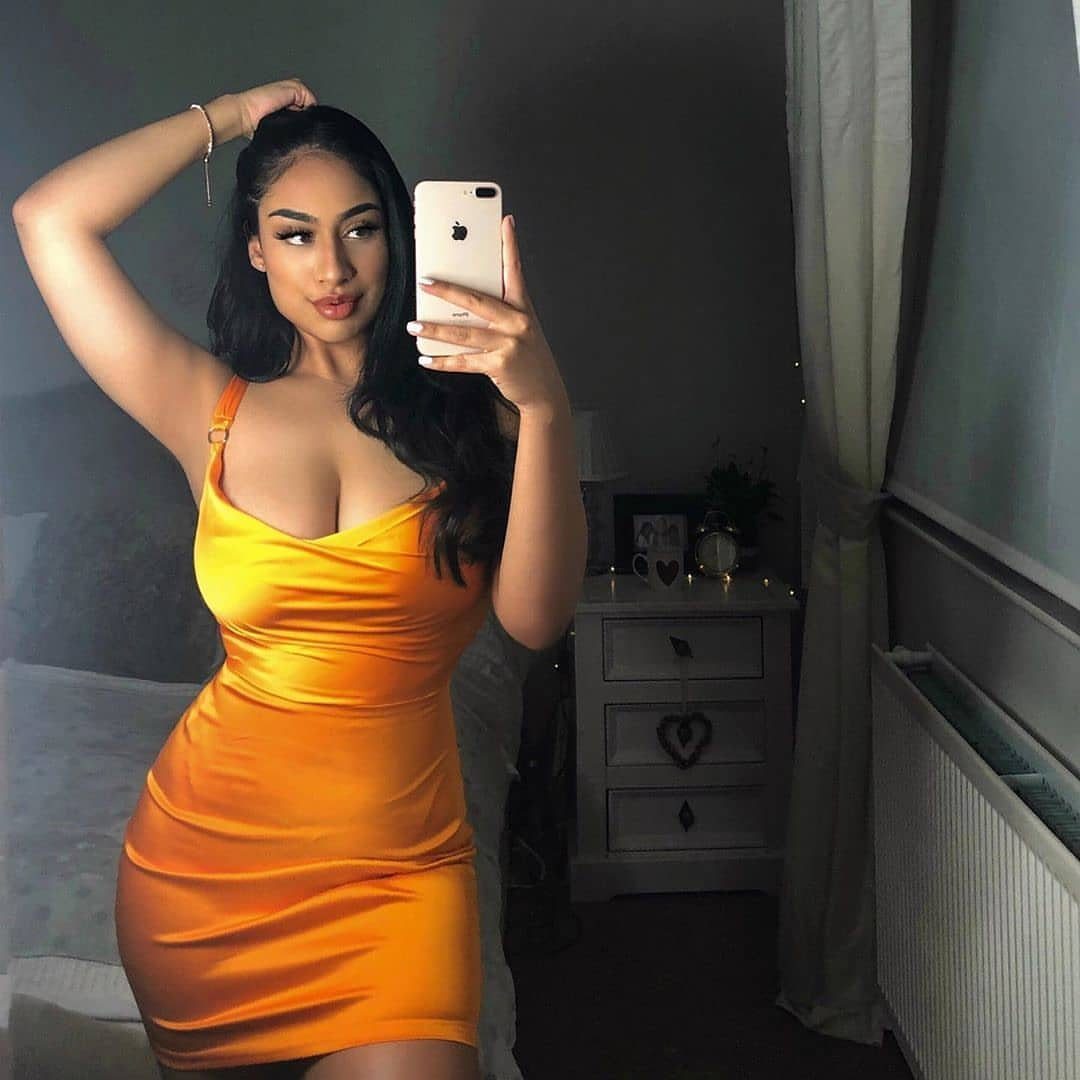 Fall Orange Outfits: 10 Ideas for Every Occasion 5 Woman in a short orange satin dress taking a mirror selfie in a bedroom