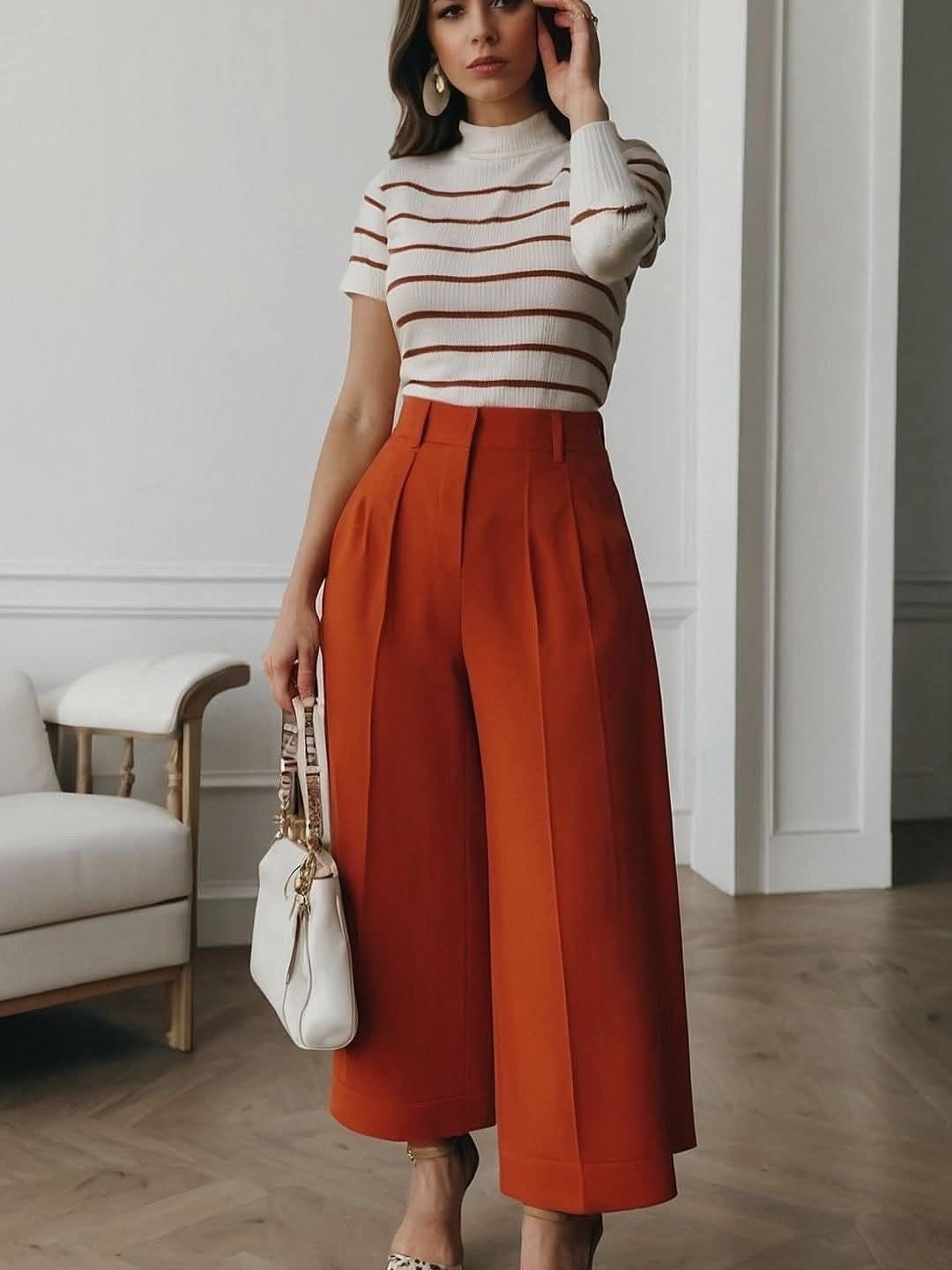 Fall Orange Outfits: 10 Ideas for Every Occasion 8 Woman wearing wide-leg orange trousers and a striped white top in a bright room