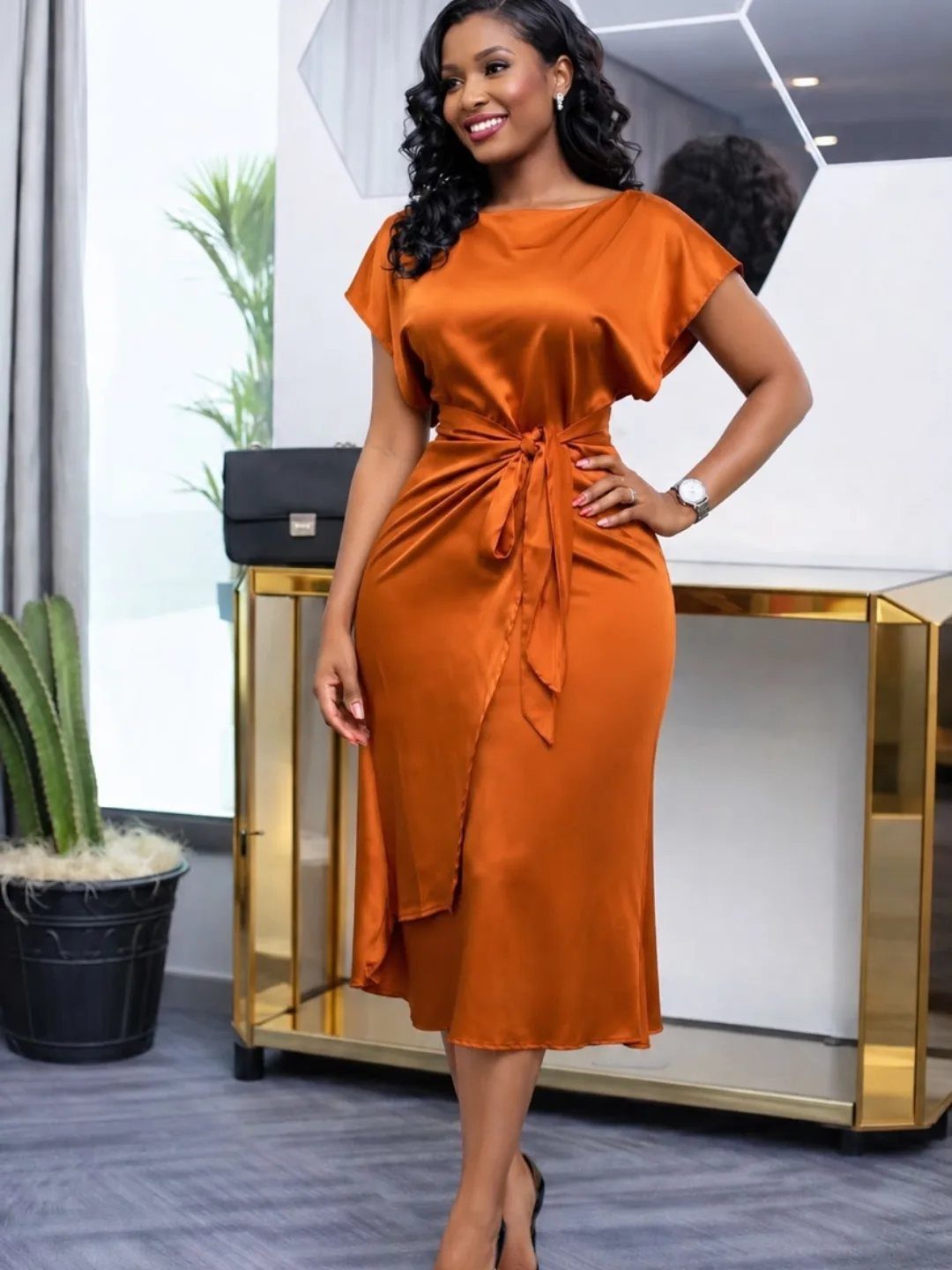 Fall Orange Outfits: 10 Ideas for Every Occasion 1 Woman wearing a burnt orange satin midi dress with a tie-waist and flutter sleeves.