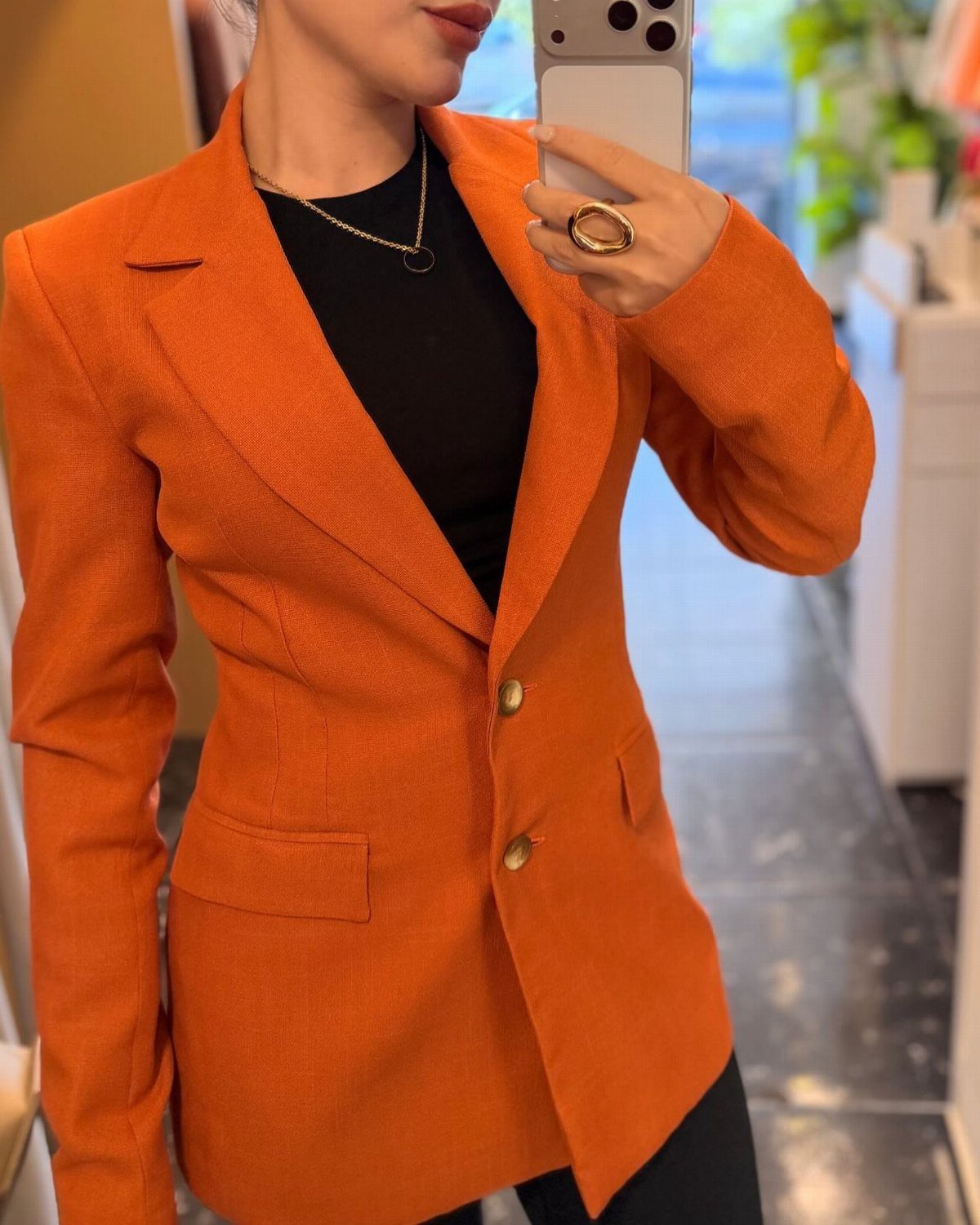 Fall Orange Outfits: 10 Ideas for Every Occasion 6 Person wearing a tailored orange blazer with gold buttons over a black top.