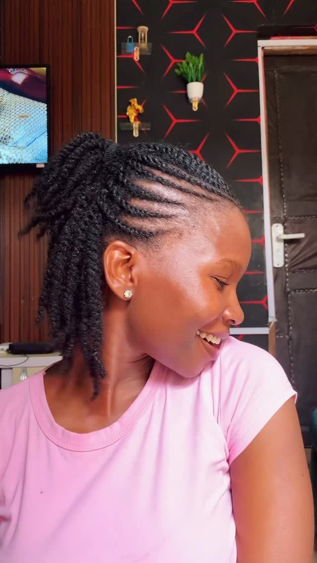 Woman with flat twist hairstyle and ponytail wearing a pink t-shirt smiling