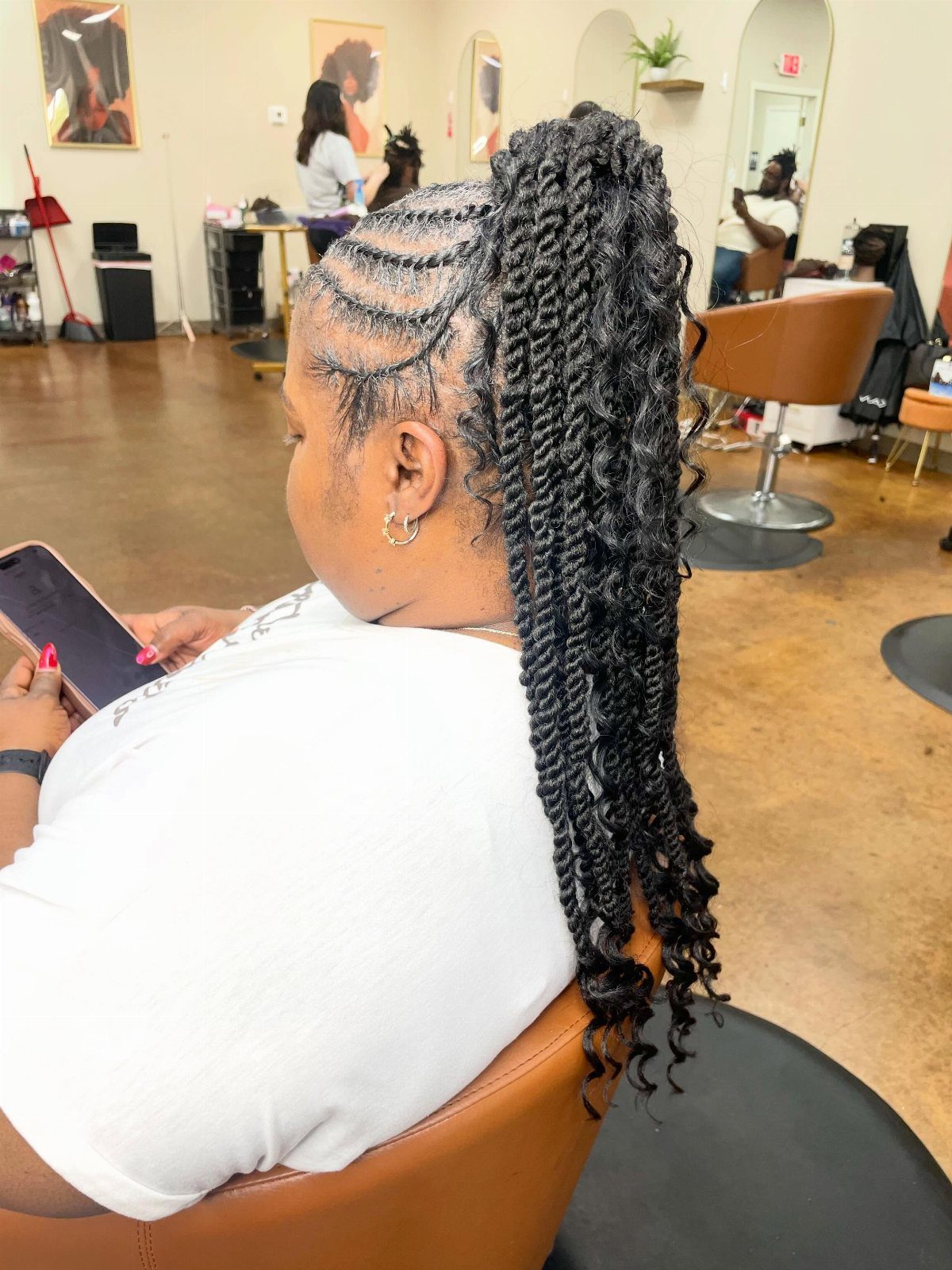 Woman with black hair styled in flat twists gathered into a high ponytail.