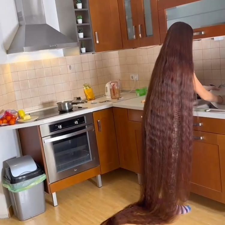 Woman with floor length straight brown hair standing in a home kitchen