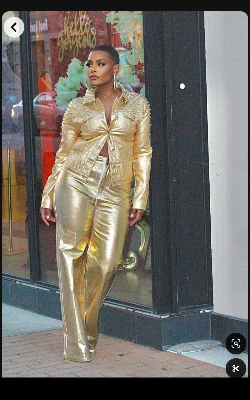 Woman wearing a metallic gold faux-leather cropped jacket and matching wide-leg trousers.