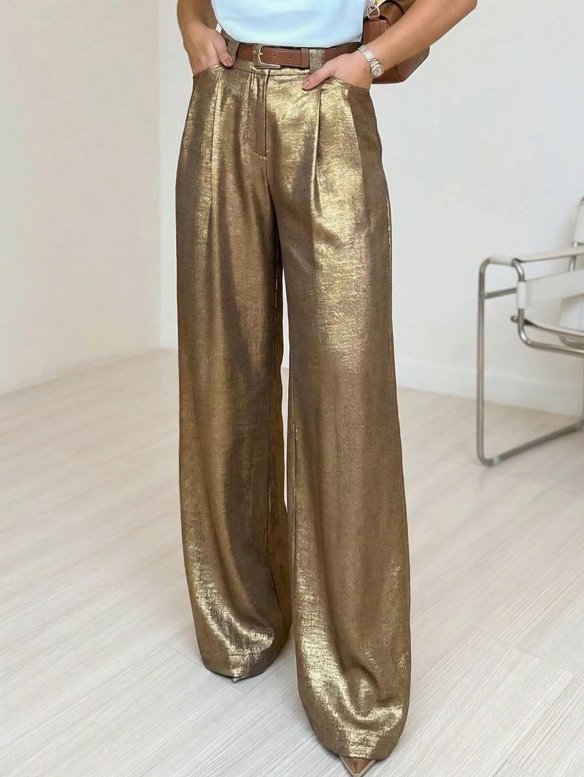 Wide-leg metallic gold trousers paired with a light blue top and brown belt.