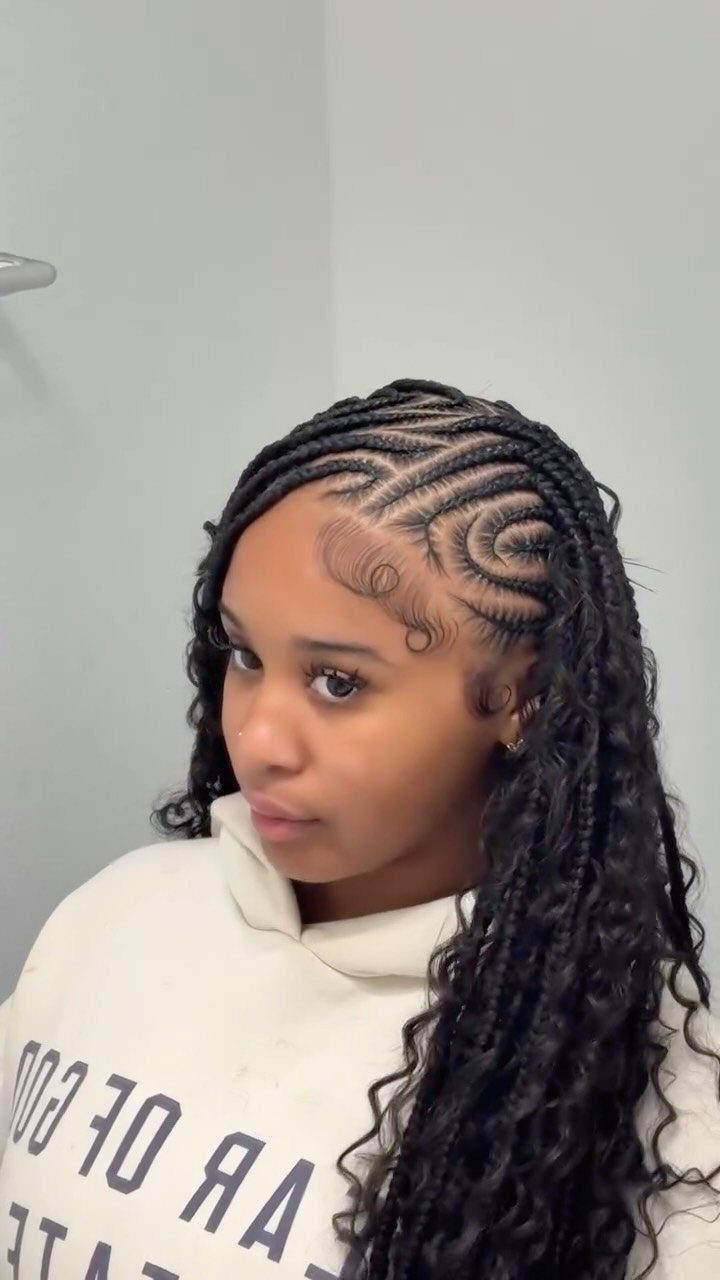 Woman with curved cornrows and long curly boho braids wearing a white hoodie.